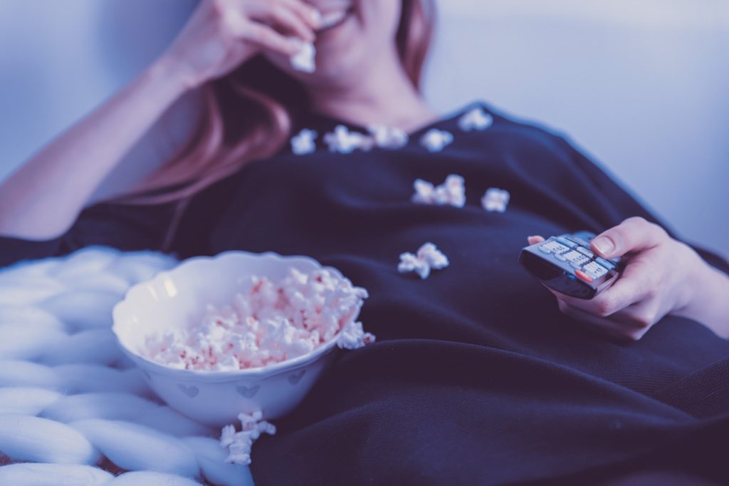 fille en train de regarder la télé avec du popcorn